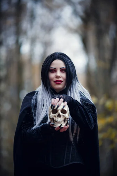 Retrato de bruxa menina em manto preto com crânio — Fotografia de Stock