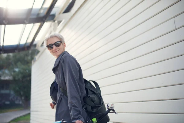 Imagem da jovem mulher com bicicleta verde contra a parede cinza — Fotografia de Stock