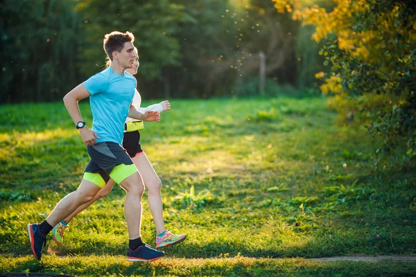 Foto einer jungen sportlichen Frau und eines Mannes beim Laufen im Park — Stockfoto