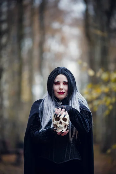 Picture of witch woman in black cloak with skull — Stock Photo, Image