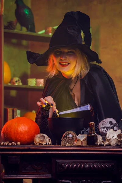 Portrait de jeune sorcière en chapeau noir avec potion de brassage de livres en pot — Photo