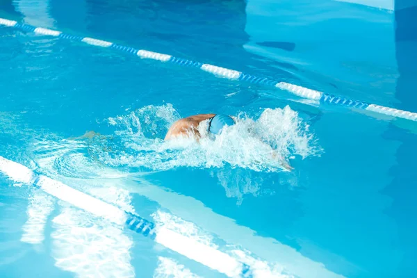 Photo of athlete in blue rubber cap floating under water in pool — Stock Photo, Image