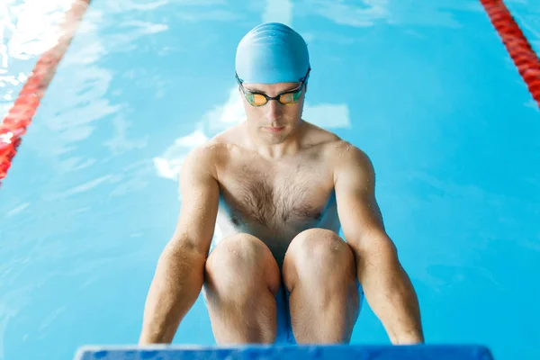 Image athlete in blue rubber cap and glasses pushing in pool
