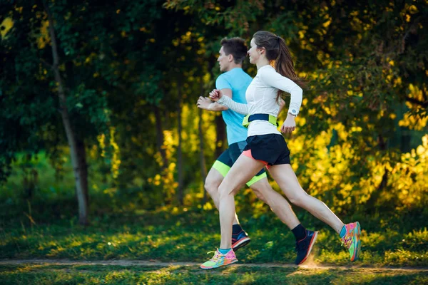 Mladý sportovec žena a muž běží v parku — Stock fotografie