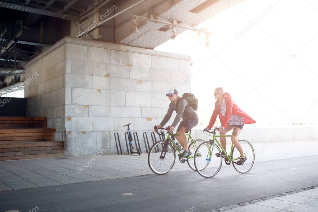 Side image of sportive woman and man riding bike
