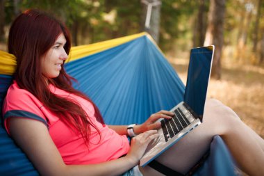 Hamakta oturmuş dizüstü bilgisayar ile mutlu esmer tarafında fotoğraf
