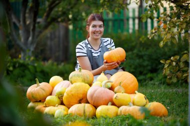 Kabak hasat yeşil çim üzerinde arasında gri önlük içinde mutlu bahçıvan kadın resim