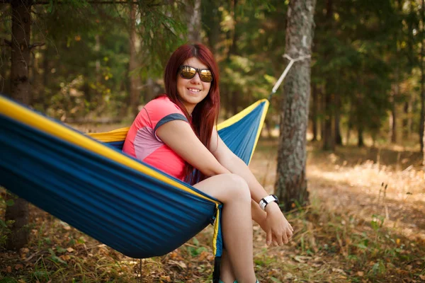 Foto de morena en gafas de sol con portátil sentado en hamaca — Foto de Stock