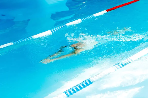 Изображение спортсмена в синем резиновом колпаке, плавающего под водой в бассейне — стоковое фото