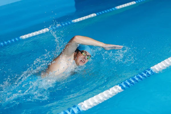 Фото спортсмена в голубой кепке, плавающего в стиле ползания в бассейне — стоковое фото