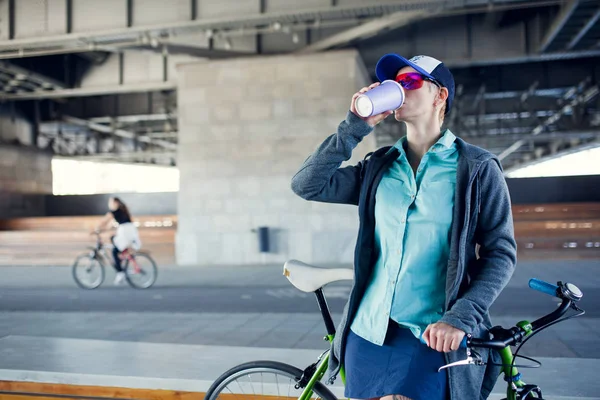 Foto del hombre bebiendo de vidrio mientras está de pie con la bicicleta —  Fotos de Stock