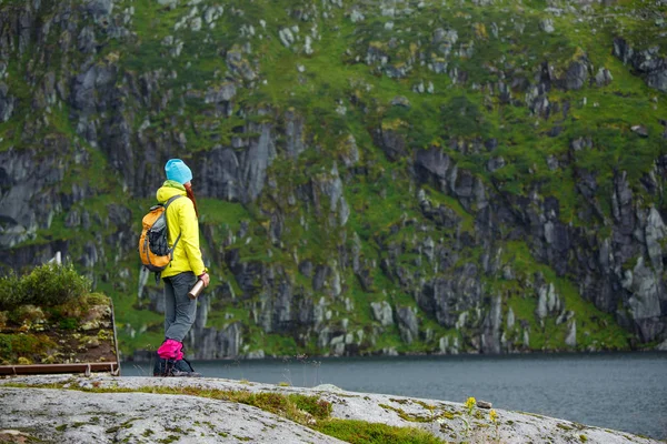 Foto von der Rückseite des Touristenmädchens mit blauer Mütze und Rucksack, das auf einem Hügel steht — Stockfoto