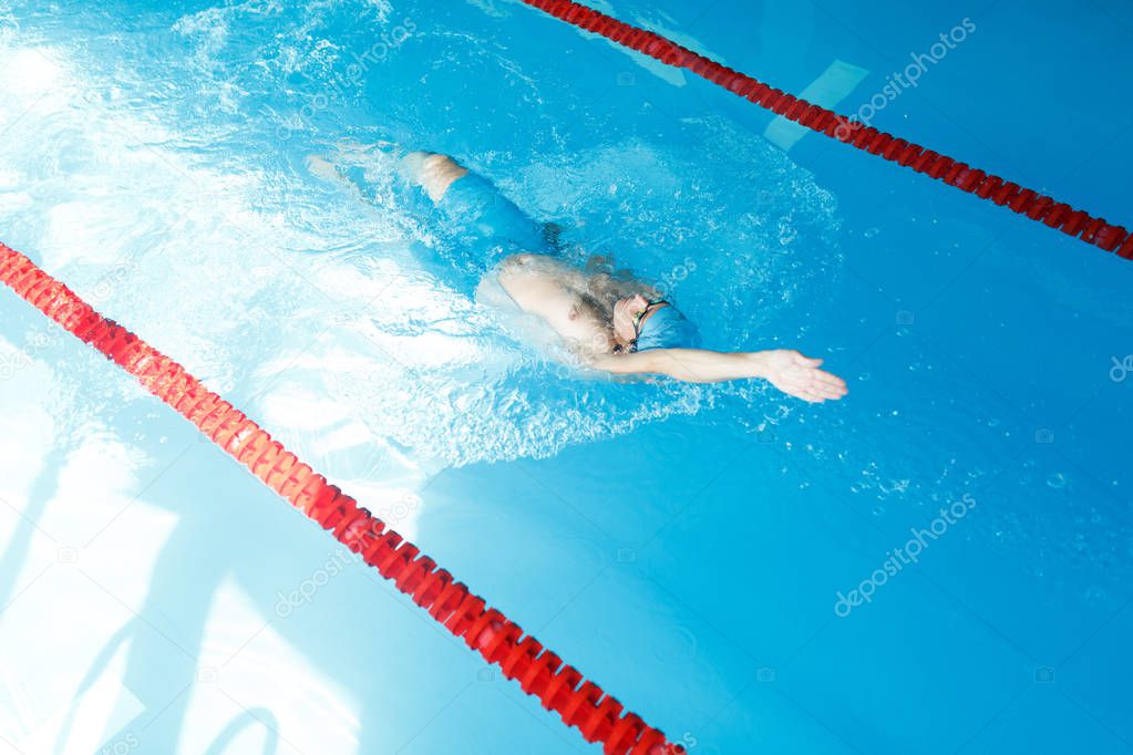 Image on top of athlete man swimming on back in swimming pool