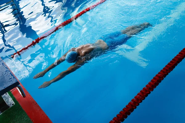 Foto op de top van atleet man in blauwe cap op pad in zwembad zwemmen — Stockfoto