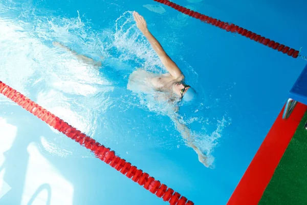 Photo sur le dessus de l'athlète homme nageant sur le dos dans la piscine — Photo