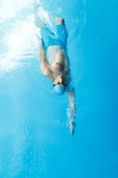Изображение на вершине молодого спортсмена в синей кепке, плавающего в бассейне — стоковое фото