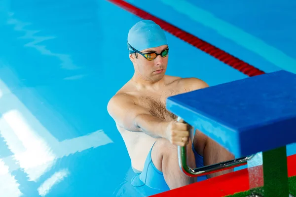 Foto van atleet zwemmer in blauwe dop aan zijkant in zwembad — Stockfoto