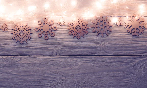 雪の上からガーランドを燃焼クリスマス木製グレー テーブルの写真. — ストック写真