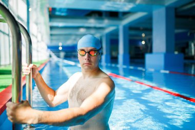 Photo of young swimmer man coming out of indoor pool clipart