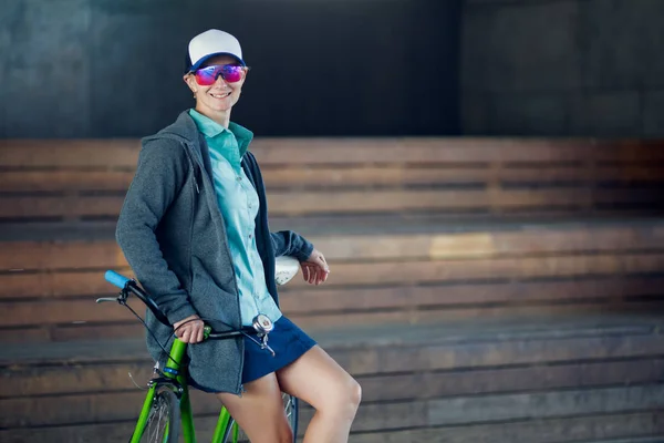 Изображение женщины в солнечных очках, стоящей с велосипедом в помещении — стоковое фото