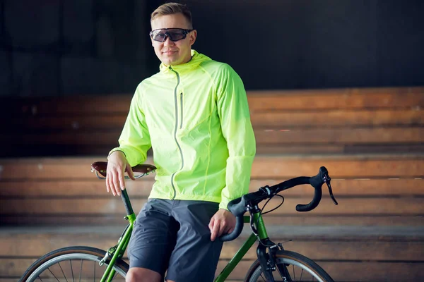 Afbeelding van de mens in zonnebril permanent met fiets binnenshuis — Stockfoto