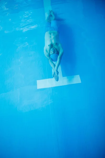 Фото на фото спортсмена, плавающего на задней части крытого бассейна — стоковое фото