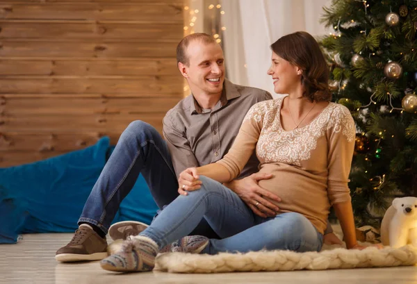 Foto van de gelukkige zwangere paar op achtergrond van versierde kerstboom — Stockfoto