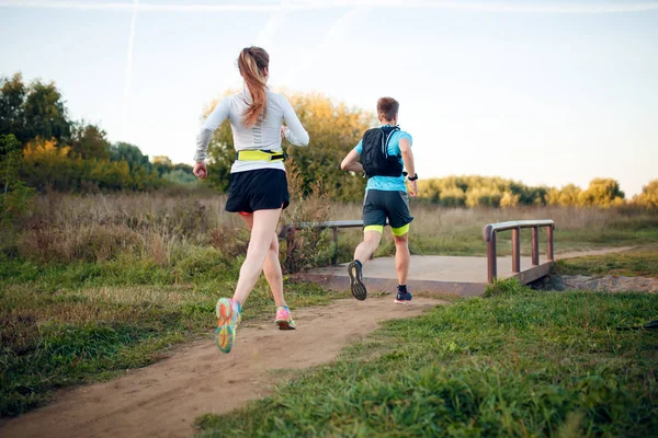 Imagem na parte de trás de mulher esportiva e homem correndo através do parque — Fotografia de Stock