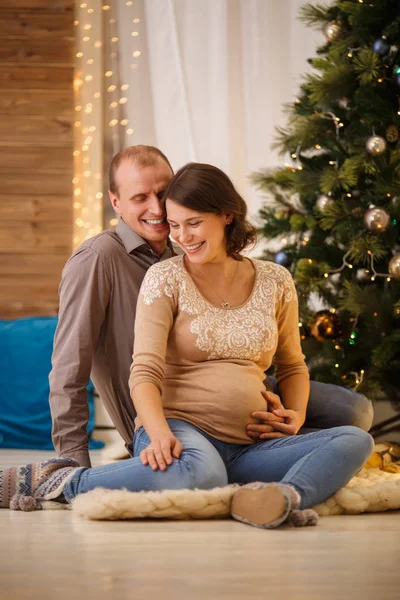 Image of happy pregnant couple on background of decorated New Year tree — Stock Photo, Image