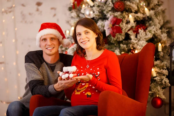 Foto de hombres alegres en gorra de Santa con regalo y mujer embarazada — Foto de Stock