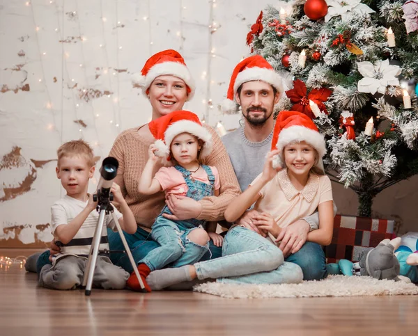 Imagem de pais, duas filhas em bonés de Santa e filho com telescópio — Fotografia de Stock