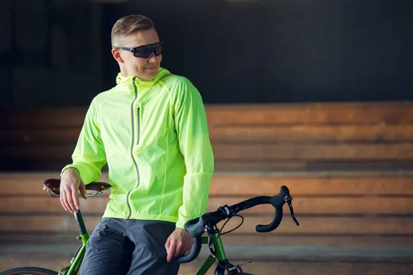 Foto van de mens in zonnebril permanent met fiets binnenshuis — Stockfoto