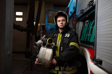 Photo of firefighter with hoses in hands on background of fire truck clipart