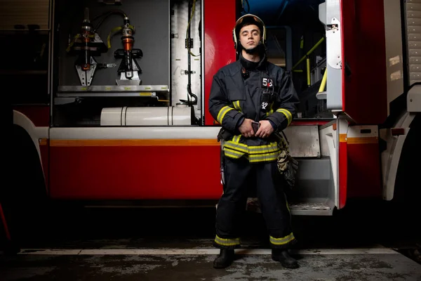 Full-length photo of man fireman on background of fire truck