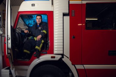 Ateş kamyonda oturan genç itfaiyeci adam görüntüsünü