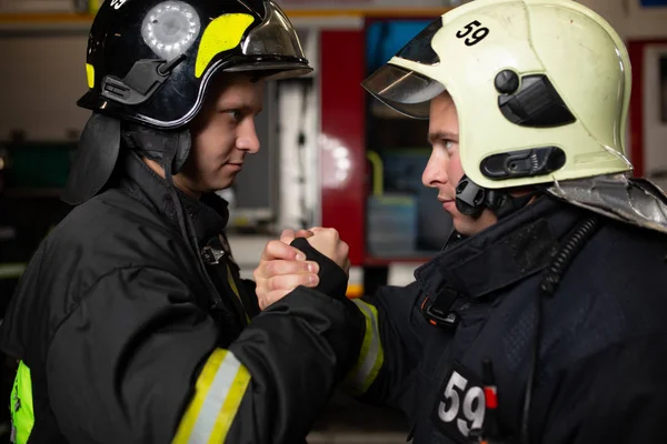 Imagem de dois bombeiros usando capacetes acenando com o aperto de mão — Fotografia de Stock