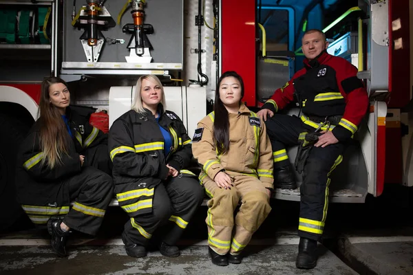 Φωτογραφία των τριών firewomen, πυροσβέστης σε φόντο πυροσβεστικό όχημα — Φωτογραφία Αρχείου