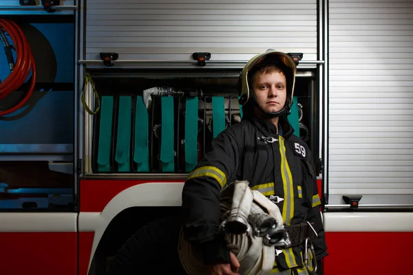 Imagem do bombeiro com mangueiras nas mãos no fundo do caminhão de bombeiros — Fotografia de Stock