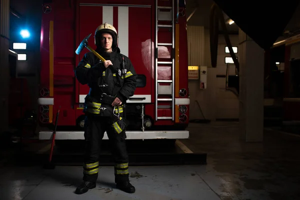 Foto eines Feuerwehrmannes mit Spitzhacke auf dem Hintergrund eines Feuerwehrfahrzeugs — Stockfoto