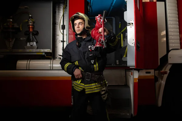 Obraz člověka hasičů s ohněm kohout na rameni pozadí hasičský vůz na stanici — Stock fotografie