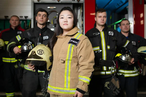 Retrato de quatro jovens bombeiros masculinos e femininos no fundo do caminhão de bombeiros — Fotografia de Stock