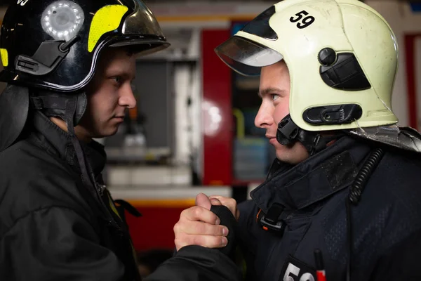 Foto dvou hasičů helmy mávat jejich handshake — Stock fotografie
