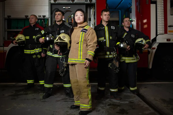 Obrázek čtyř mladých mužů a žen hasičů na pozadí hasičský vůz — Stock fotografie
