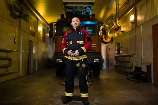 Ganztägiges Foto eines Feuerwehrmannes vor dem Hintergrund eines Feuerwehrfahrzeugs — Stockfoto