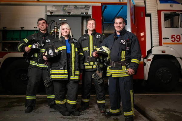 Εικόνα πλήρους μήκους τριών νέων φωτιά ανδρών και γυναικών σε φόντο πυροσβεστικό όχημα — Φωτογραφία Αρχείου