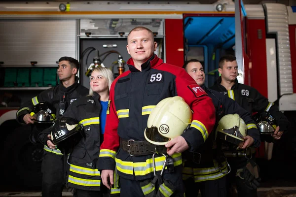 Bild von vier Feuerwehrmännern und einer Frau im Hintergrund eines Feuerwehrfahrzeugs — Stockfoto