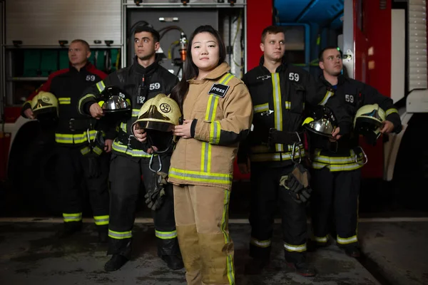 Imagen de cuatro jóvenes bomberos masculinos y femeninos en el fondo del camión de bomberos —  Fotos de Stock