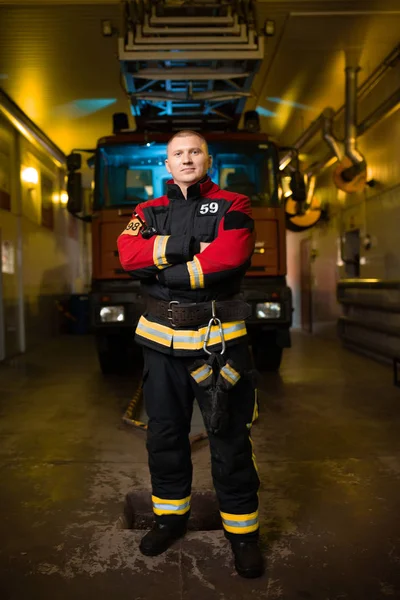 Full-length photo of young firefighter on background of fire truck at station — Stock Photo, Image