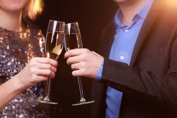 Образ женщины в блестящем платье и мужчины с бокалами вина с шампанским на черном фоне — стоковое фото