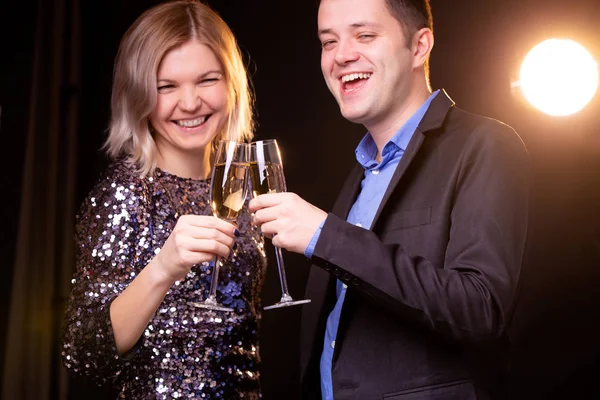 Φωτογραφία του χαμογελαστό γυναίκα σε λαμπρή φόρεμα και άνδρες με ποτήρια κρασιού με σαμπάνια σε μαύρο φόντο — Φωτογραφία Αρχείου